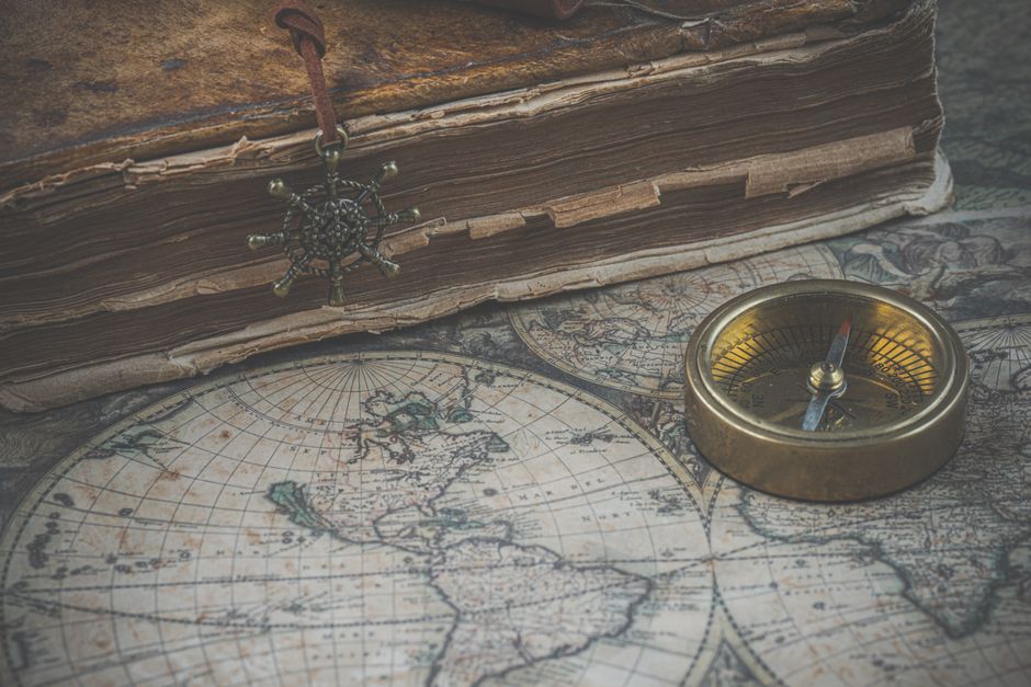 Old map and compass alongside an antique book for a vintage exploration theme.